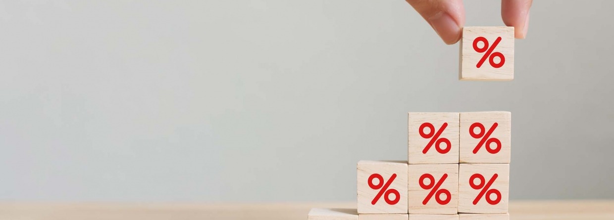 Hand die een houten kubusblok met percentage teken zet in opwaartse richting op dezelfde andere blokjes